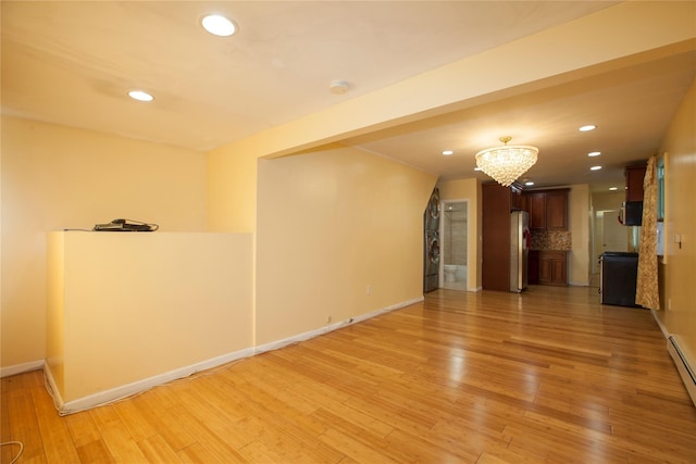 spare room featuring light wood-style floors, recessed lighting, a notable chandelier, and baseboards