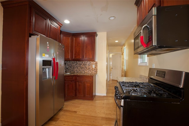 kitchen with reddish brown cabinets, light wood finished floors, appliances with stainless steel finishes, backsplash, and recessed lighting