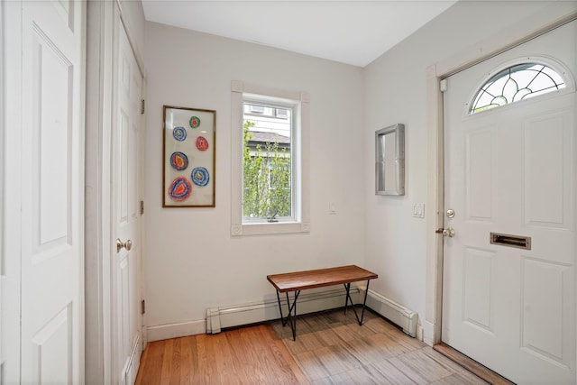 foyer with a baseboard heating unit, plenty of natural light, baseboards, and light wood-style floors