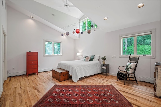 bedroom featuring a baseboard heating unit, light wood-type flooring, multiple windows, high vaulted ceiling, and recessed lighting