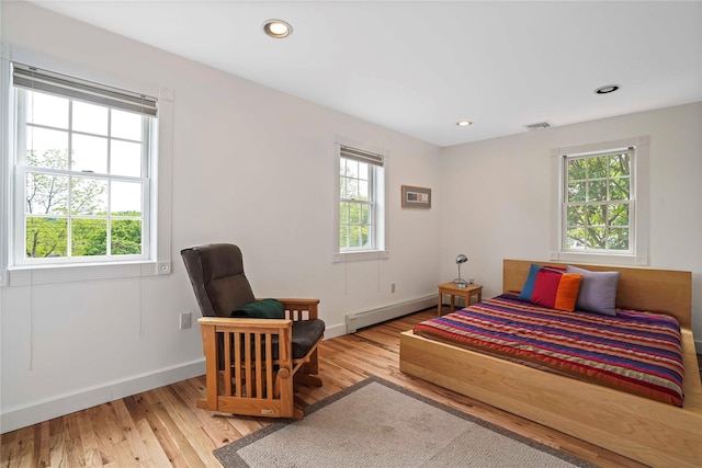 bedroom featuring a baseboard heating unit, wood finished floors, baseboards, and recessed lighting