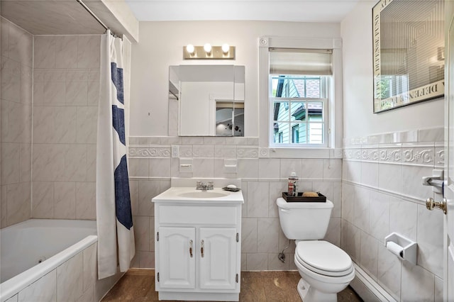 bathroom with tile walls, toilet, tiled shower / bath combo, and vanity