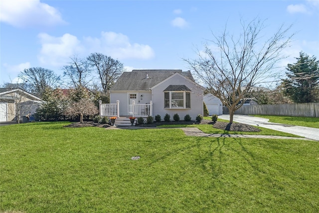 view of front facade with a deck, an outbuilding, fence, concrete driveway, and a front lawn