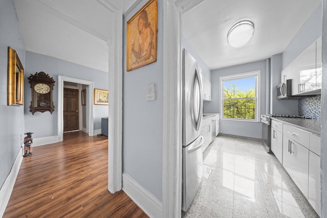 45-08 40th St Unit F32, Sunnyside, NY 11104 - kitchen featuring baseboards, light wood-type flooring, light countertops, white cabinetry, and appliances with stainless steel finishes