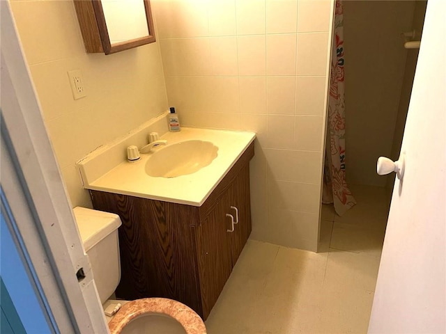 bathroom with tile patterned floors, toilet, tile walls, and vanity