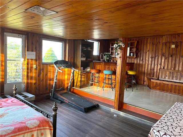 workout room with wooden ceiling, indoor bar, wooden walls, and wood-type flooring