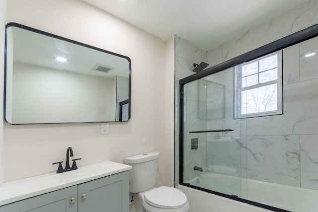 bathroom featuring toilet, bath / shower combo with glass door, vanity, and visible vents