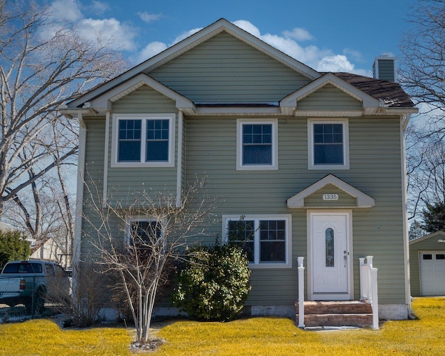 view of front facade featuring a garage, a chimney, and a front lawn