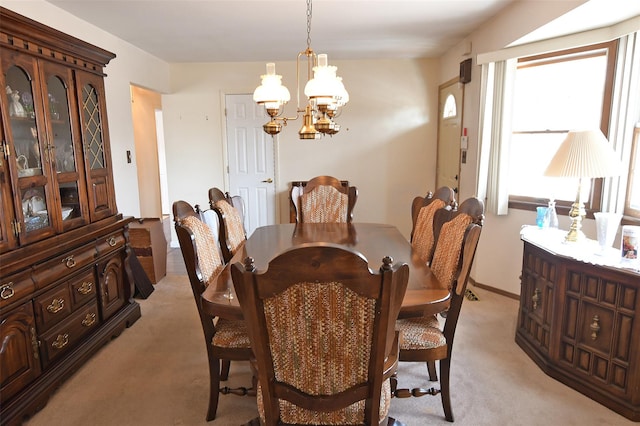 dining area with an inviting chandelier, baseboards, and light colored carpet