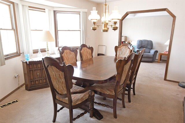 dining area with baseboards, an inviting chandelier, visible vents, and light colored carpet