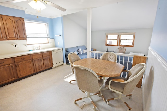 dining room featuring a healthy amount of sunlight, light floors, crown molding, and a wainscoted wall