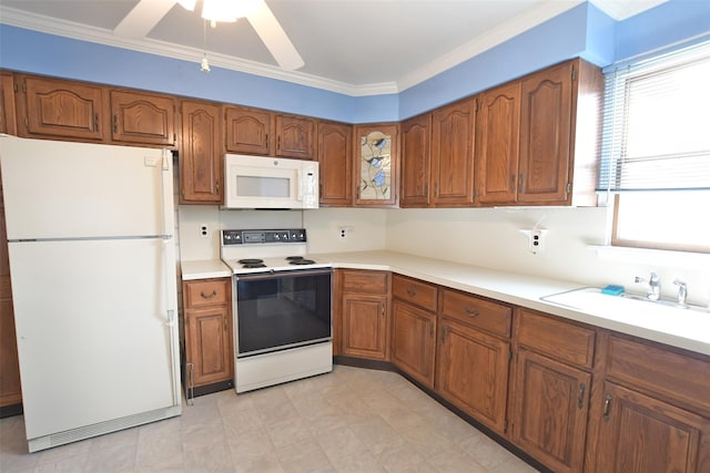 kitchen with brown cabinetry, white appliances, light countertops, and a sink