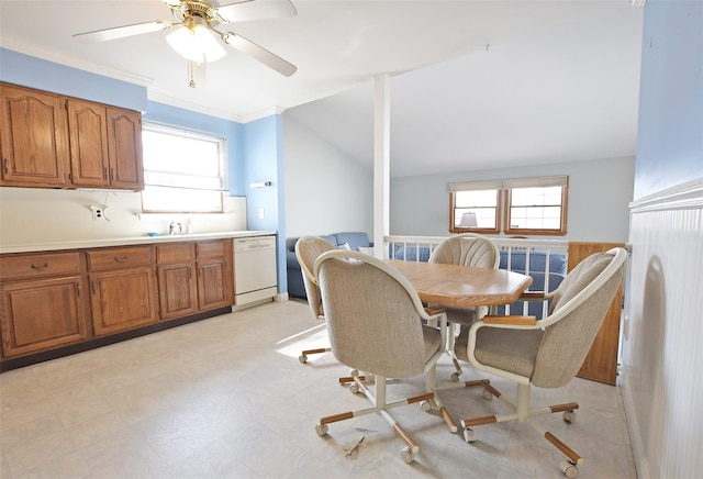 dining space with light floors, plenty of natural light, vaulted ceiling, and crown molding