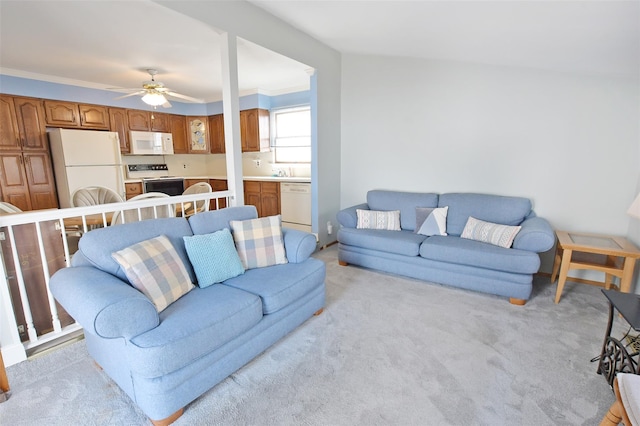 living room with light carpet, ornamental molding, and a ceiling fan