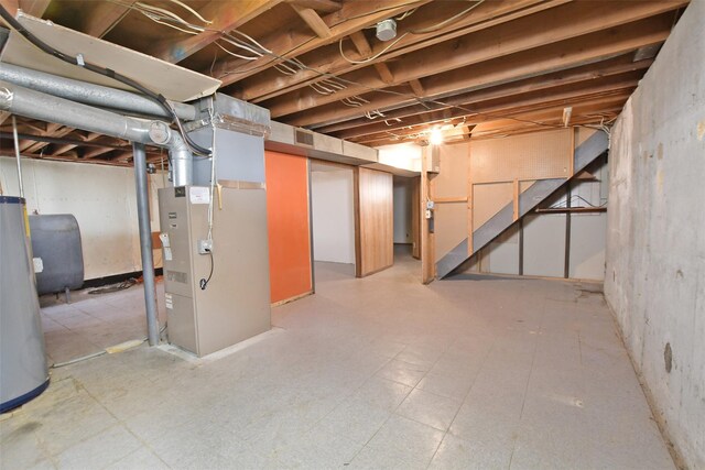 unfinished below grade area with heating unit, visible vents, water heater, tile patterned floors, and heating fuel