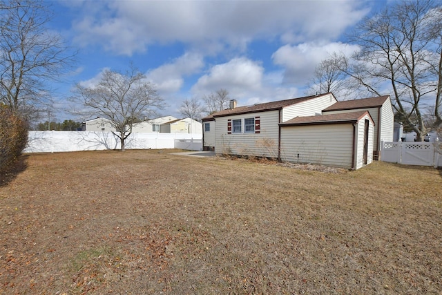 back of property with a fenced backyard, a gate, a chimney, and a yard