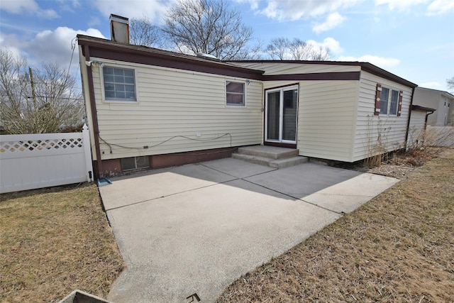 rear view of property with a patio, a chimney, and fence