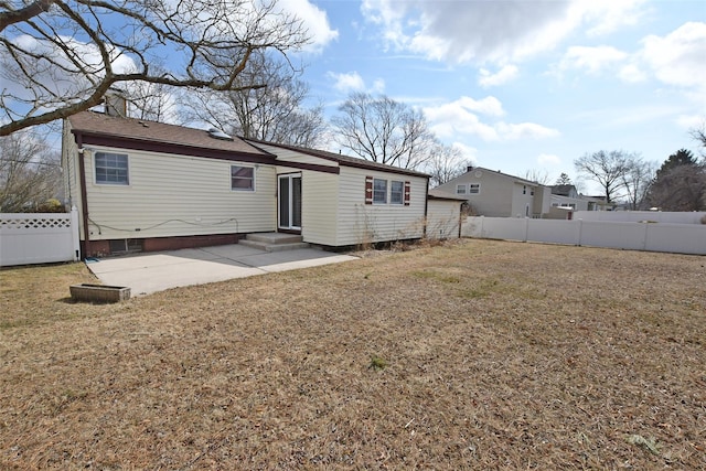 back of house featuring entry steps, a patio area, a lawn, and a fenced backyard