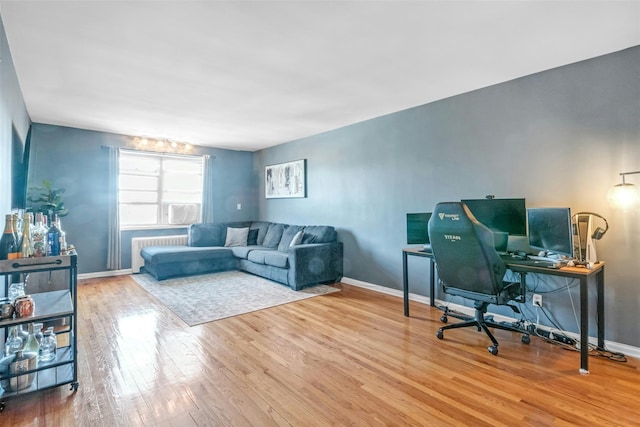 home office with radiator heating unit, wood finished floors, and baseboards