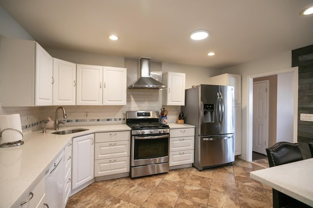 kitchen featuring stainless steel appliances, light countertops, white cabinets, a sink, and wall chimney range hood