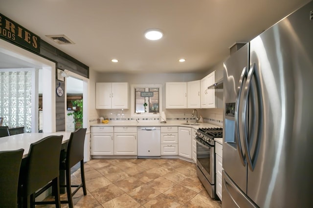 kitchen with light countertops, appliances with stainless steel finishes, a sink, and white cabinetry