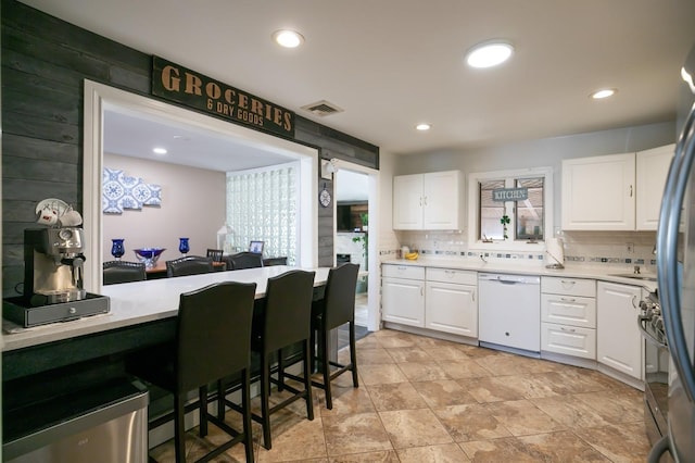 kitchen with light countertops, visible vents, decorative backsplash, white cabinets, and dishwasher