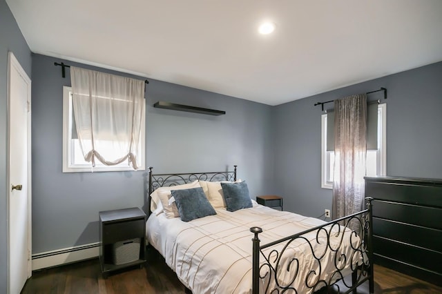 bedroom with a baseboard heating unit and dark wood-style floors