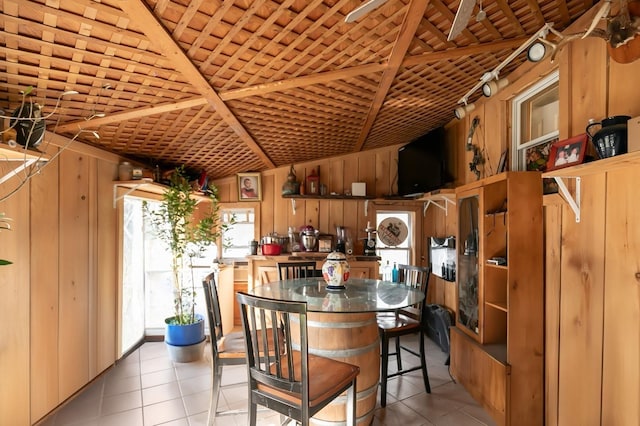 kitchen with wooden walls, a breakfast bar area, brown cabinets, and light tile patterned flooring