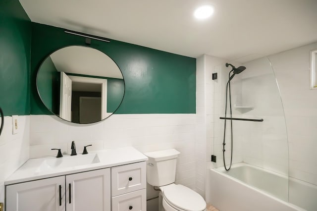 bathroom with shower / bathing tub combination, tile walls, toilet, and vanity