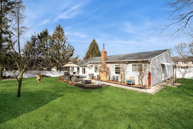 rear view of property featuring a patio, a lawn, a chimney, and fence