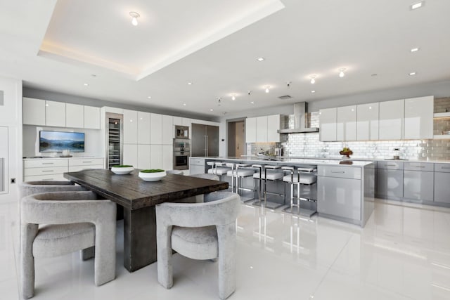 dining area featuring a tray ceiling, light tile patterned flooring, and recessed lighting