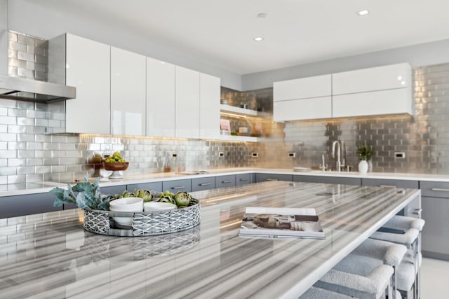 kitchen with light countertops, wall chimney range hood, decorative backsplash, and modern cabinets