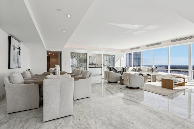 living room featuring marble finish floor, visible vents, and a tray ceiling