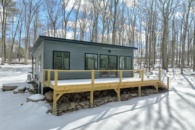 snow covered rear of property featuring a deck