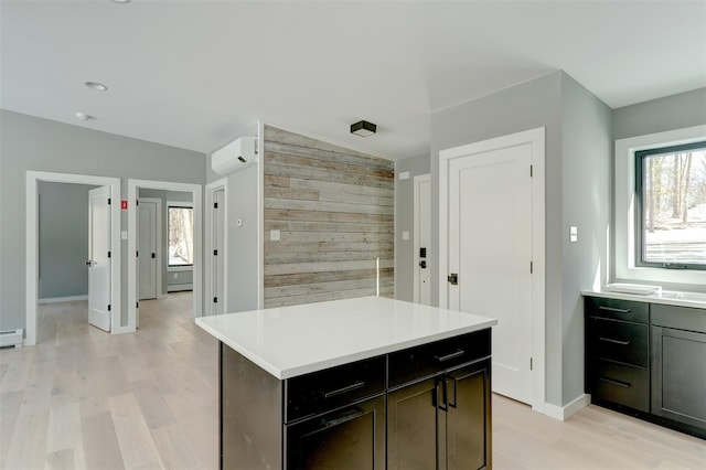 kitchen with a kitchen island, light wood-type flooring, a wall mounted air conditioner, and a healthy amount of sunlight