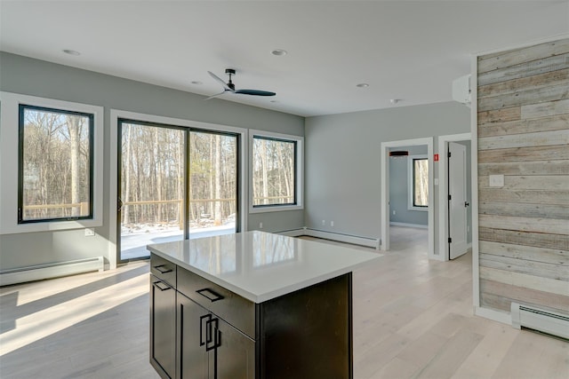 kitchen featuring a baseboard radiator, light wood-type flooring, wooden walls, and a center island