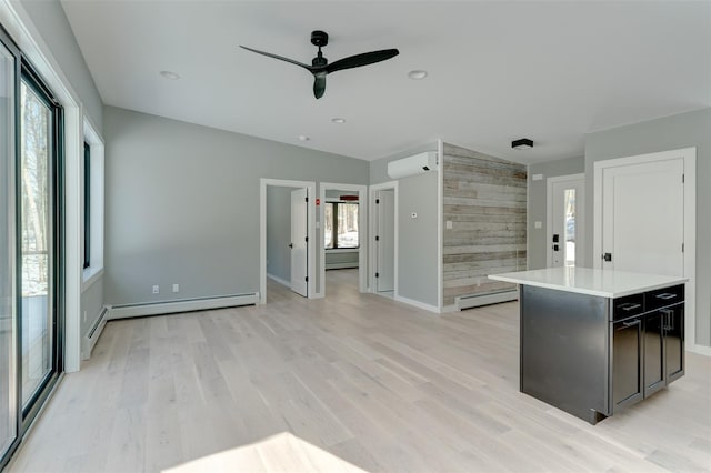 kitchen featuring light wood-type flooring, a center island, a wall unit AC, wood walls, and a baseboard radiator