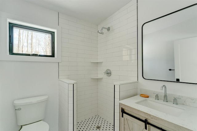 bathroom featuring a tile shower, vanity, and toilet