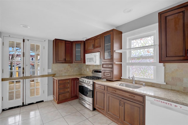 kitchen with white appliances, tasteful backsplash, glass insert cabinets, and a sink