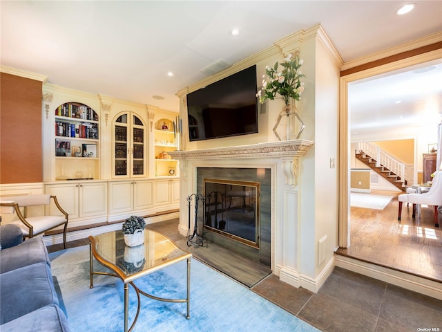 living room with a fireplace with flush hearth, ornamental molding, stairs, built in shelves, and recessed lighting