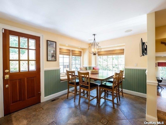 dining space with wainscoting and a notable chandelier