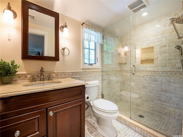 full bathroom featuring toilet, a shower stall, visible vents, and tile walls