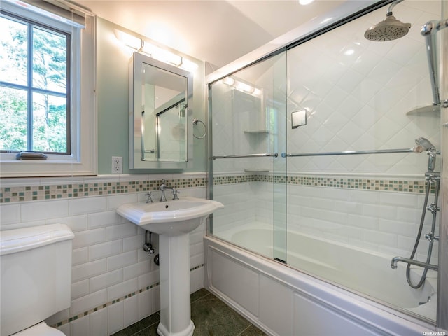 full bathroom with a wainscoted wall, tile walls, toilet, enclosed tub / shower combo, and a sink