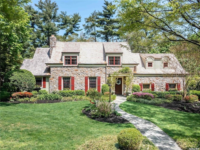 view of front of house featuring stone siding, a high end roof, and a front yard