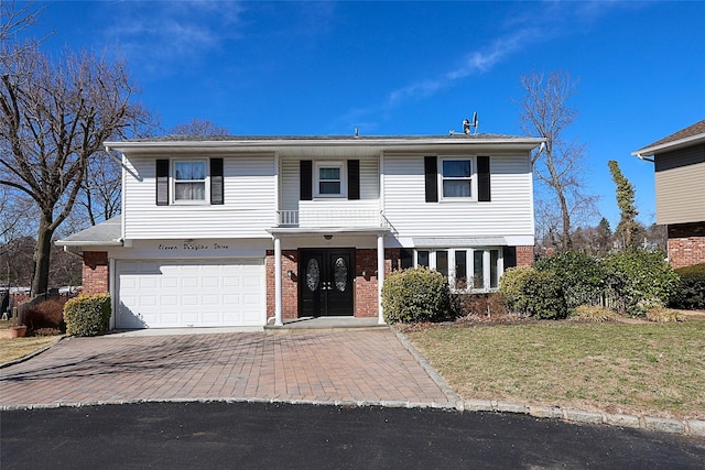 traditional home featuring decorative driveway, a front yard, a garage, and brick siding