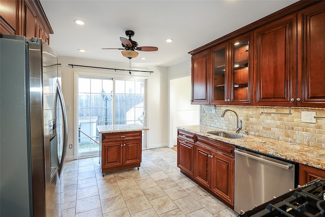 kitchen featuring tasteful backsplash, ceiling fan, light stone counters, stainless steel appliances, and a sink