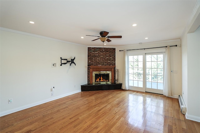 unfurnished living room featuring light wood-style flooring, ornamental molding, baseboard heating, a brick fireplace, and ceiling fan