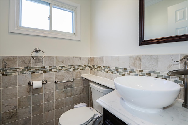 bathroom featuring vanity, tile walls, toilet, and a wainscoted wall