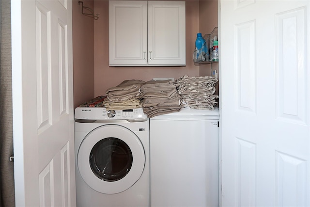 clothes washing area featuring cabinet space and washer and clothes dryer