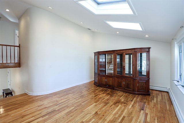 empty room with a baseboard heating unit, lofted ceiling with skylight, recessed lighting, and light wood-style floors